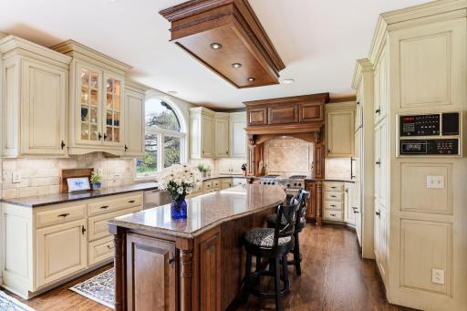The gourmet kitchen boasts two-tone cabinetry that blends rich wood tones with crisp painted finishes for a striking, upscale look.