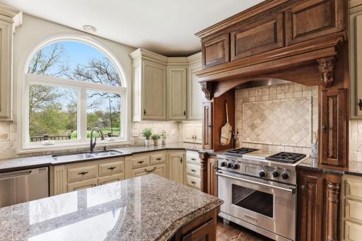 Granite countertops provide generous prep space, complemented by built-in stainless-steel appliances designed for serious culinary work.