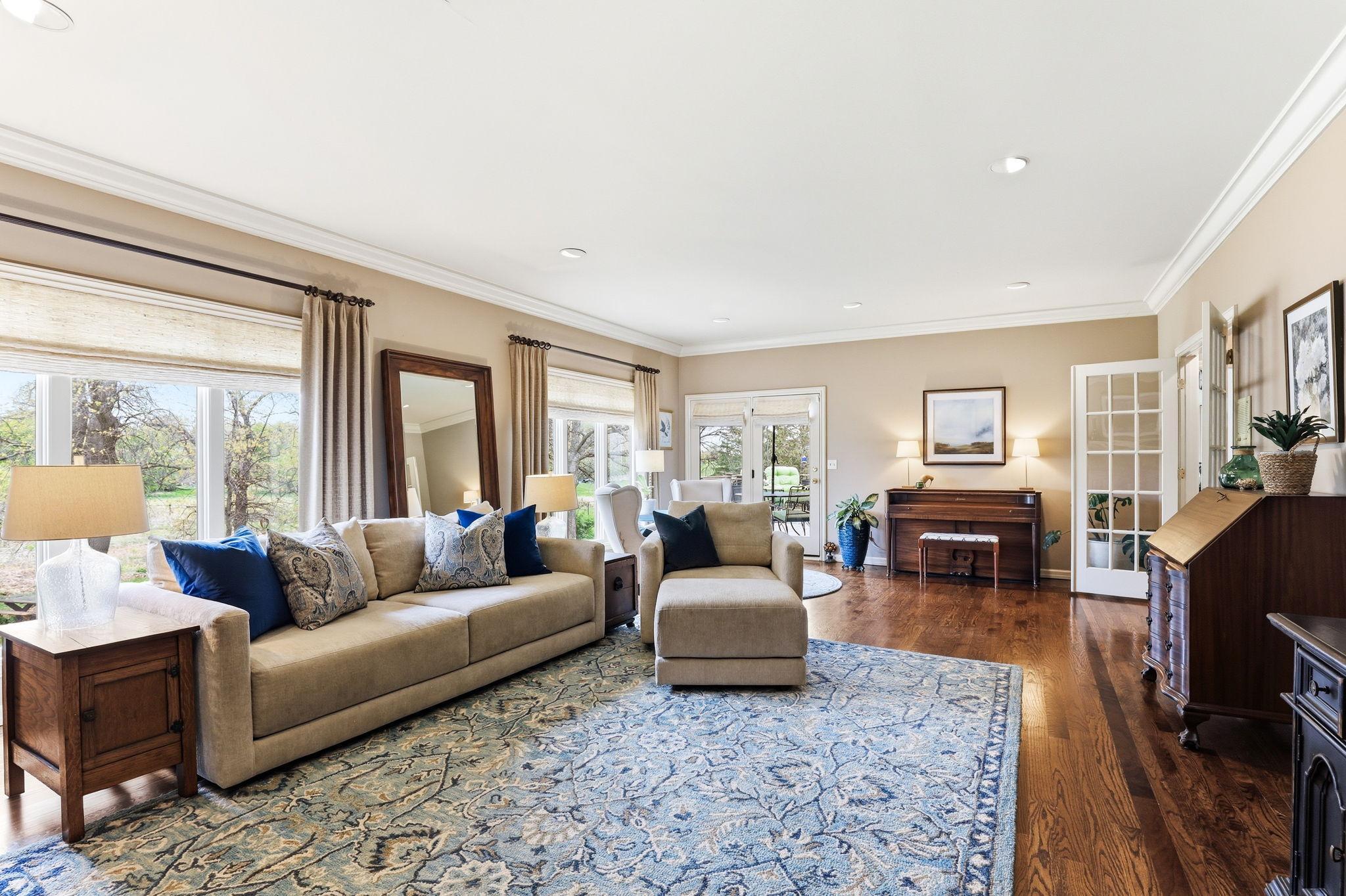 Beautifully detailed crown molding frames the ceiling with classic sophistication. Soft recessed lighting is strategically placed throughout the space, casting a warm, even glow and large windows enhance the airy feel.