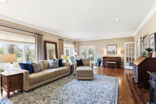Beautifully detailed crown molding frames the ceiling with classic sophistication. Soft recessed lighting is strategically placed throughout the space, casting a warm, even glow and large windows enhance the airy feel.