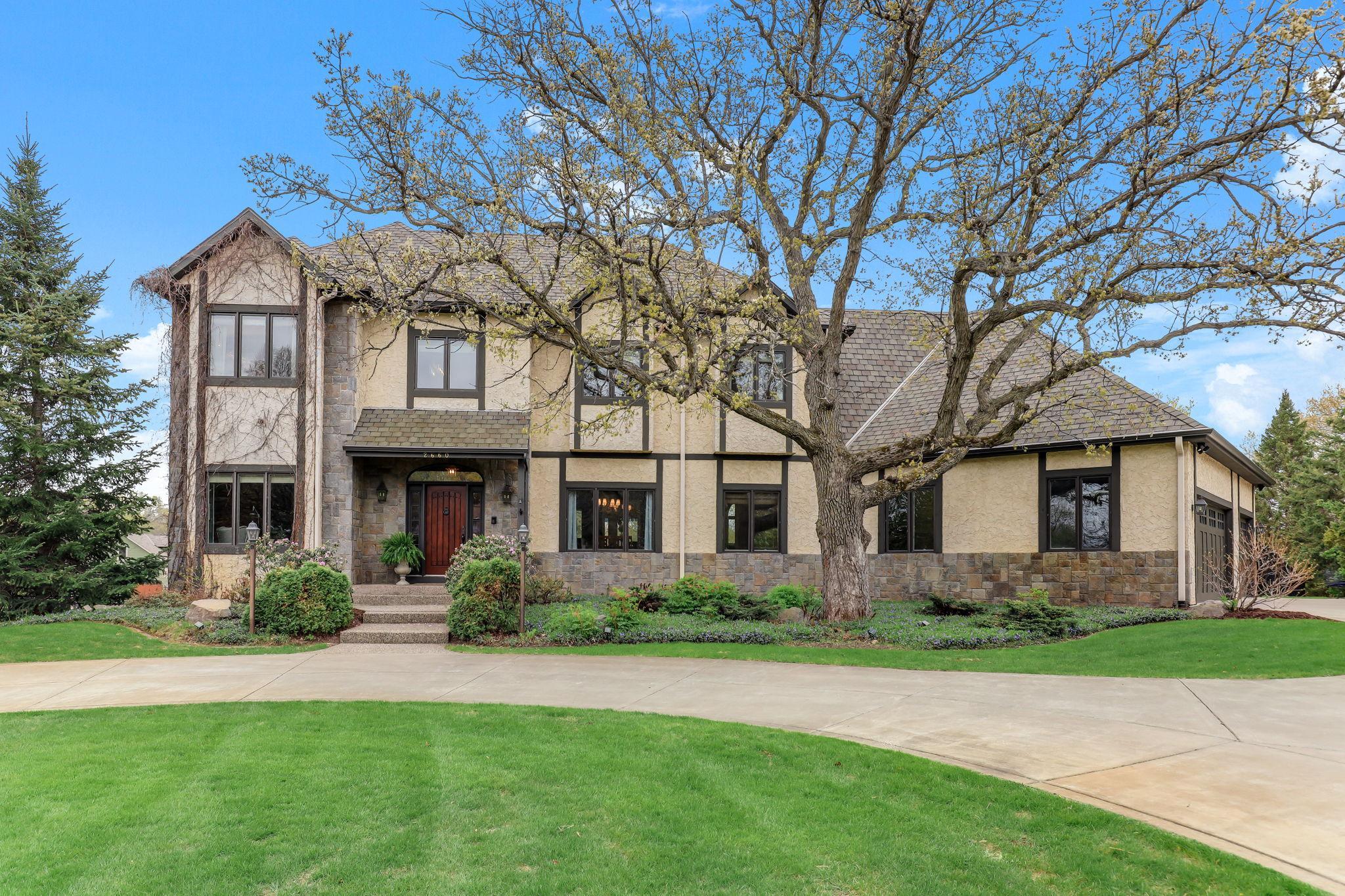 This striking two-story executive home commands attention with its grand façade, towering windows, and architectural symmetry.