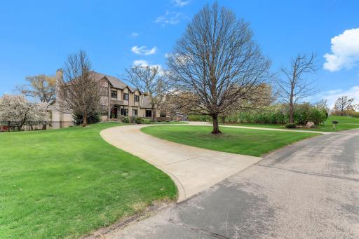 In front, a wide concrete circle driveway forms a dramatic sweep, creating a grand sense of arrival.