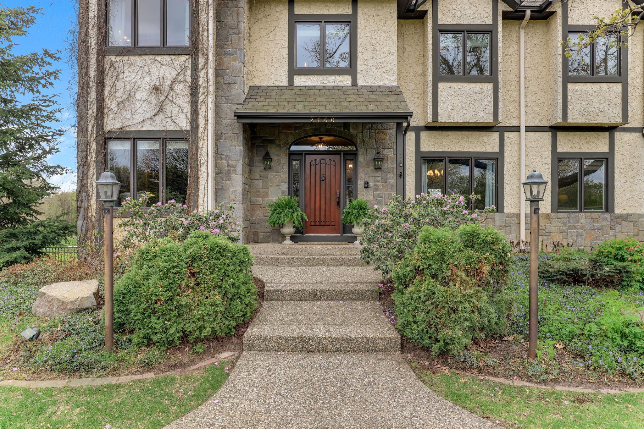 A stately entrance draws you in with a sweeping approach lined by manicured landscaping and subtle lighting.