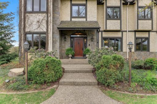 A stately entrance draws you in with a sweeping approach lined by manicured landscaping and subtle lighting.