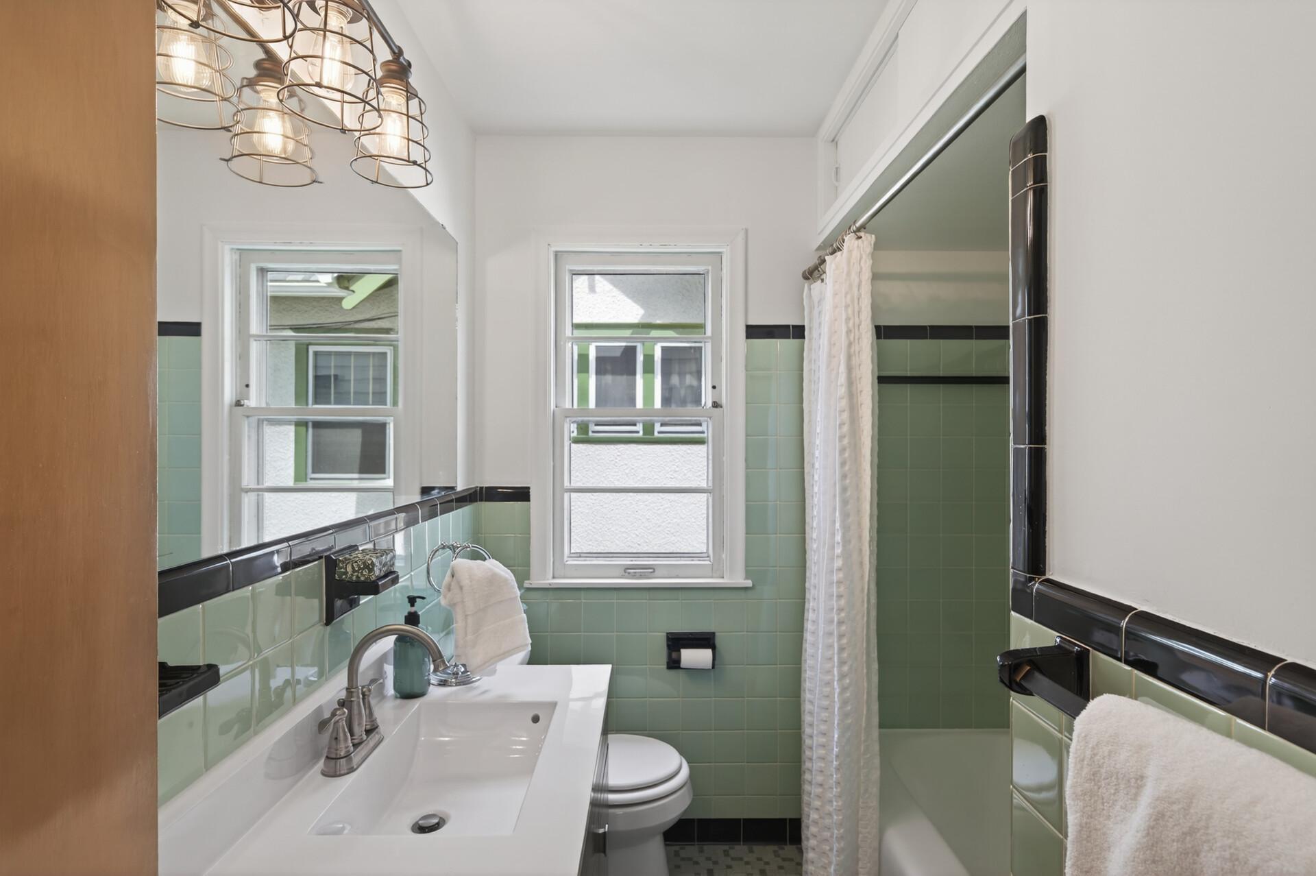 Downstairs full bath features the original green and black tile.