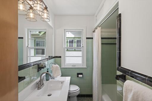 Downstairs full bath features the original green and black tile.