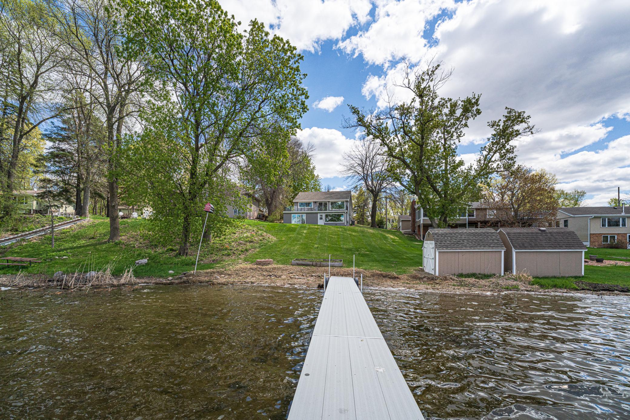 Modern updates include updated flooring, RENOVATED BATHROOMS, a gas fireplace, a four-season porch with a modern hot tub, and updated exterior features including newer vinyl siding and a NEW COMPOSITE DECK with glass railings