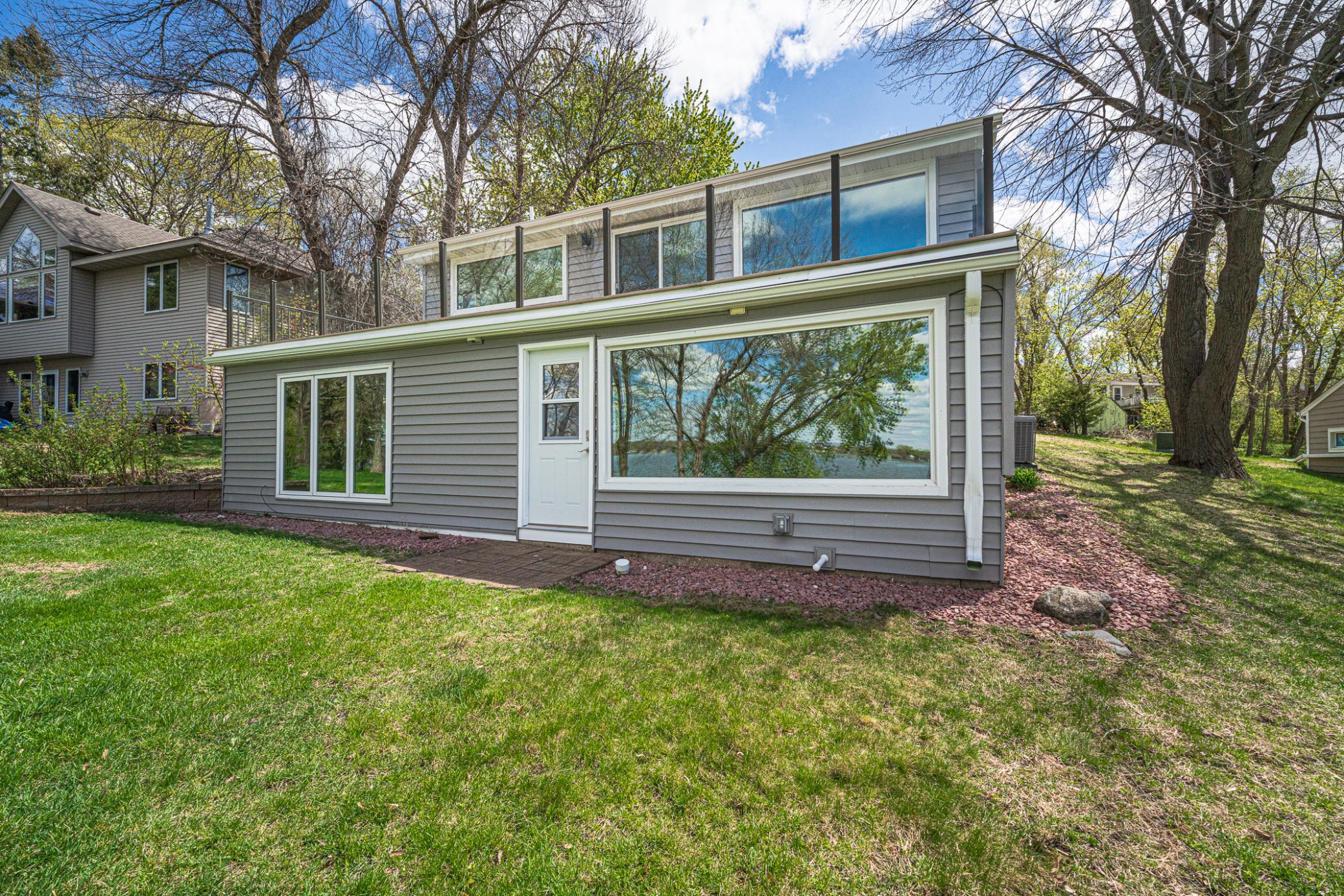The back of this walkout home showcases the new windows that offer unobstructed views of the lake from nearly every room in the house, including the four-season porch off the lower level.