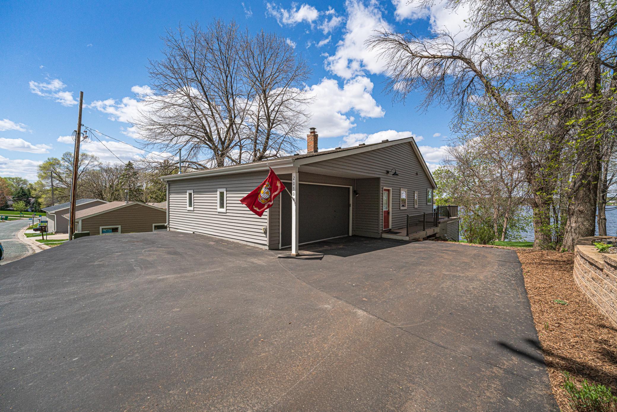 The garage door has been freshly painted, and the new composite deck wraps around the back to a 30' x 10' outdoor living space with glass railings.