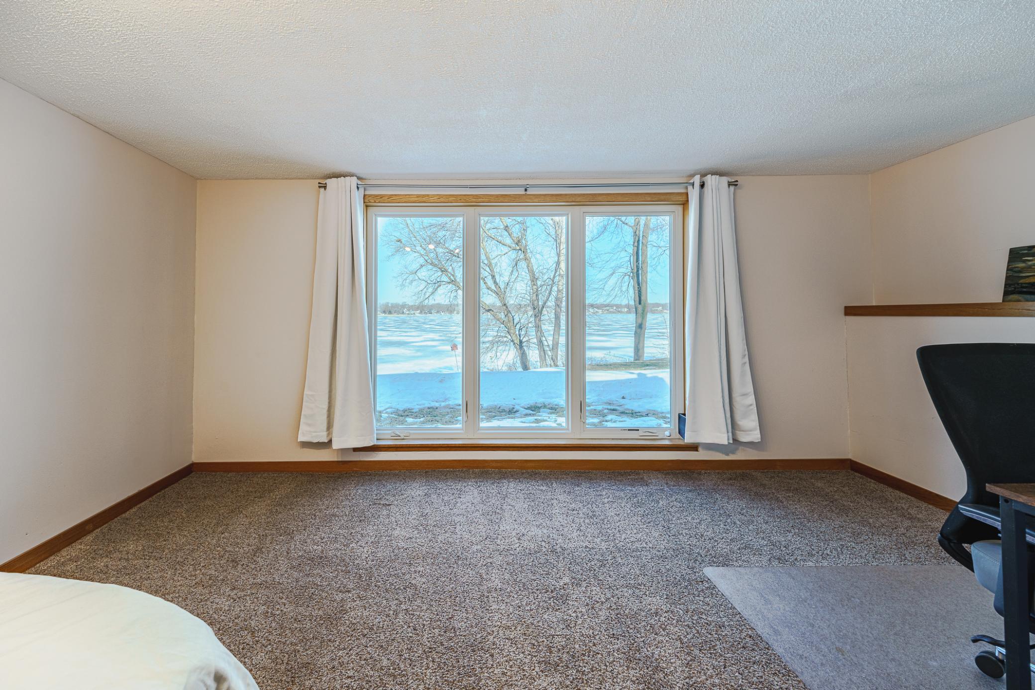 The second bedroom includes a large seating area, and has a HUGE FLOOR-TO-CEILING ANDERSEN WINDOW that showcases the lake view! There is also a large closet.