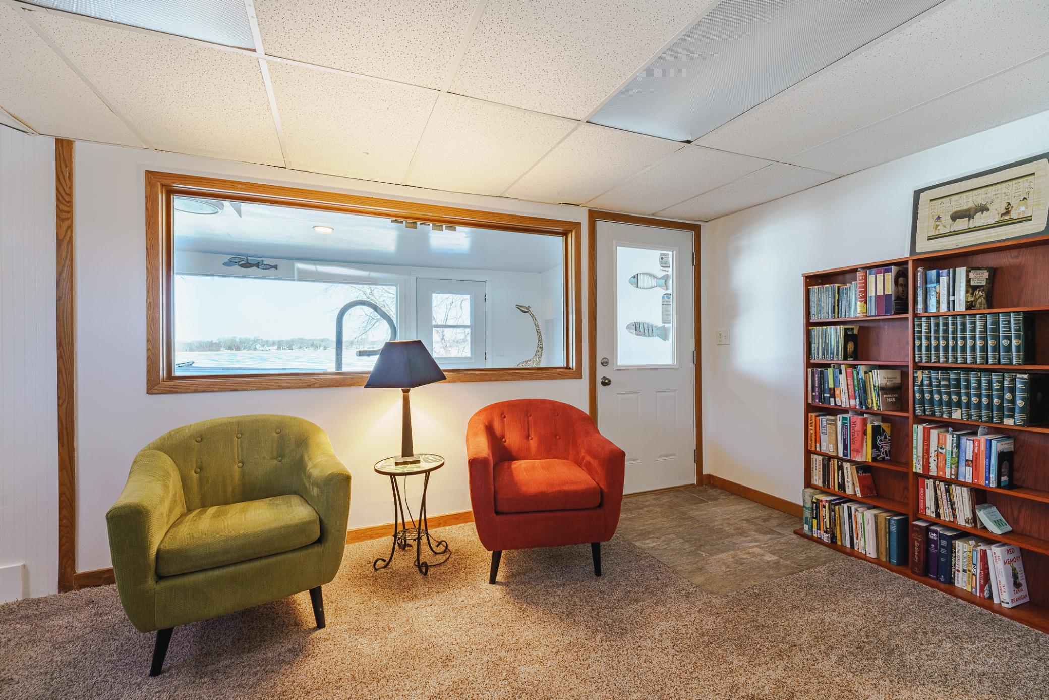 The walkout lower level offers additional living space, plus the sleeping rooms and TWO bathrooms. This intimate family room lies at the base of the staircase, with broad lake views that can be seen through the four-season porch.