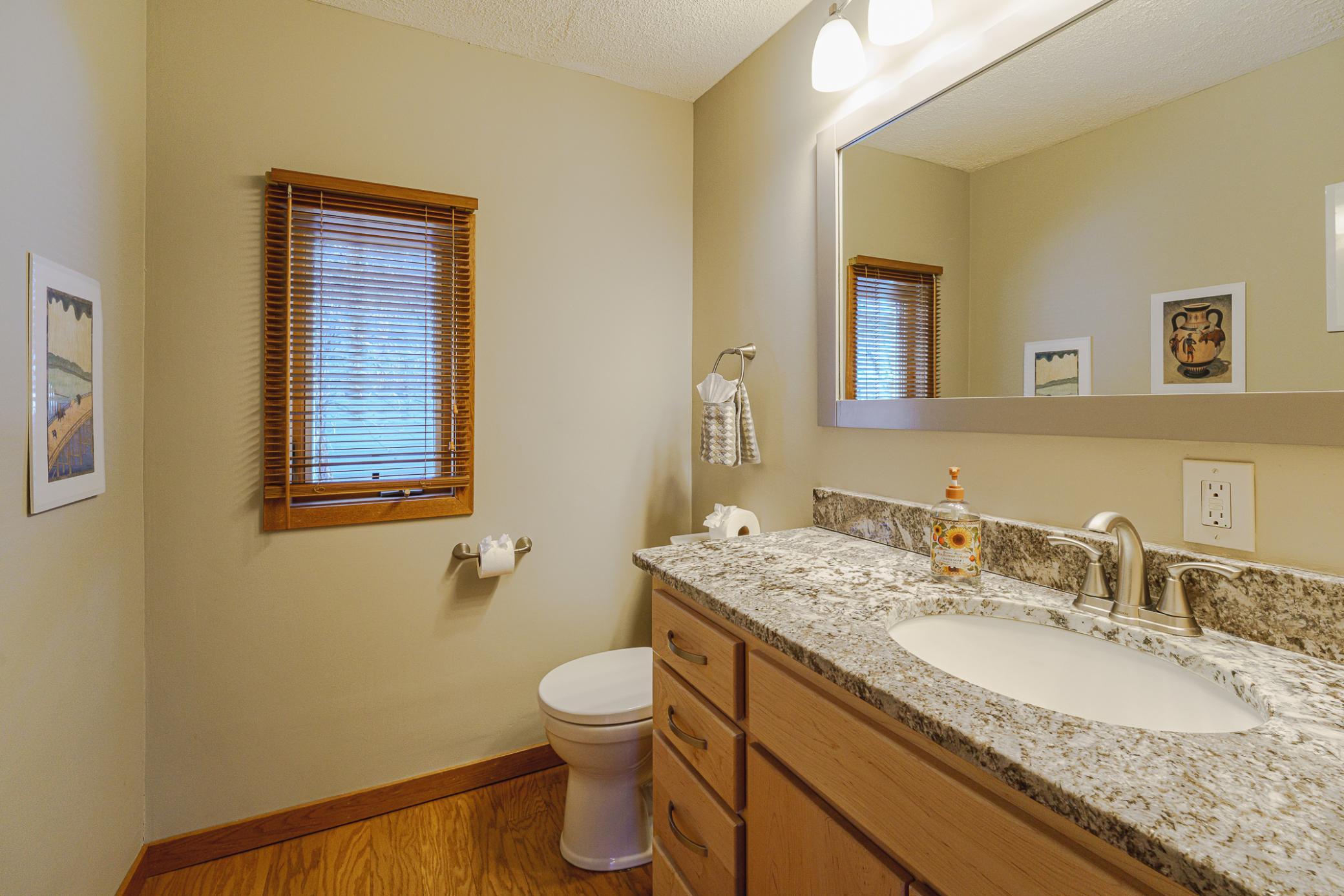 The half bathroom was renovated, and features new flooring, a new vanity by Metro Cabinets, and granite surfaces.