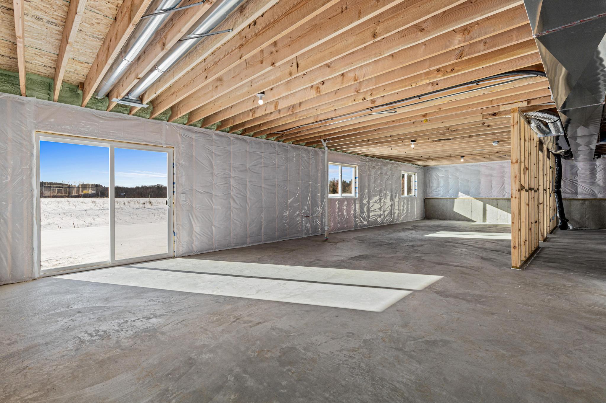 Unfinished Walkout Lower Level. Photo taken of another home with similar plan and finishes. Photos and renderings may not depict actual plan, materials, & finishes may vary. All measurements are approximate.