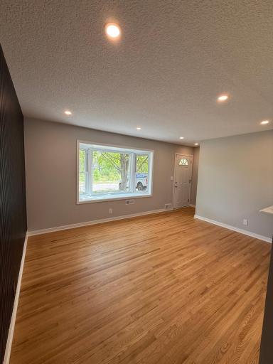 Main level living room with recessed lighting and refinished oak floors