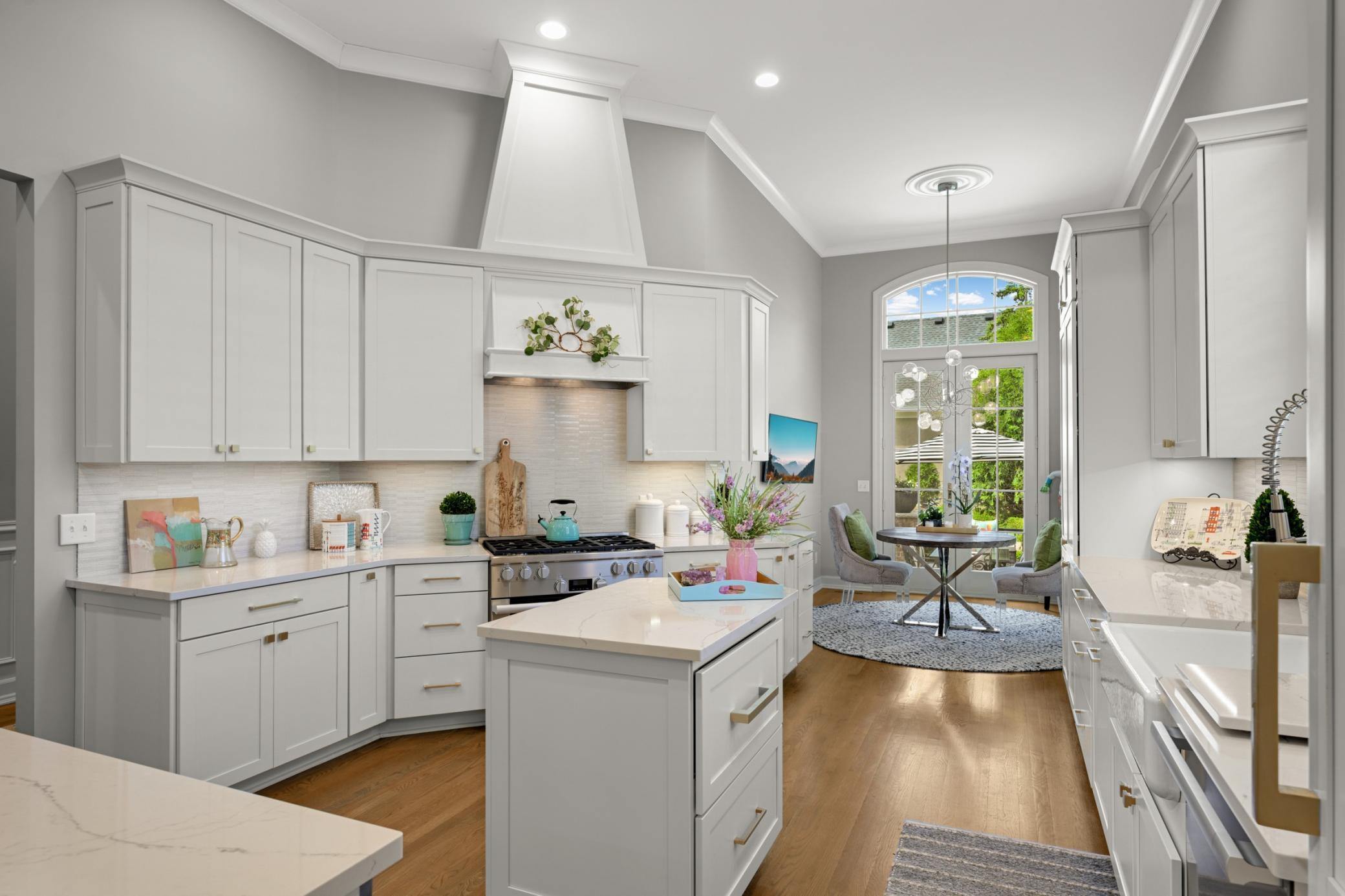 The Remodeled center Island kitchen features enameled cabinetry, Cambria Quartzsite countertops, a farm sink and a pretty backsplash