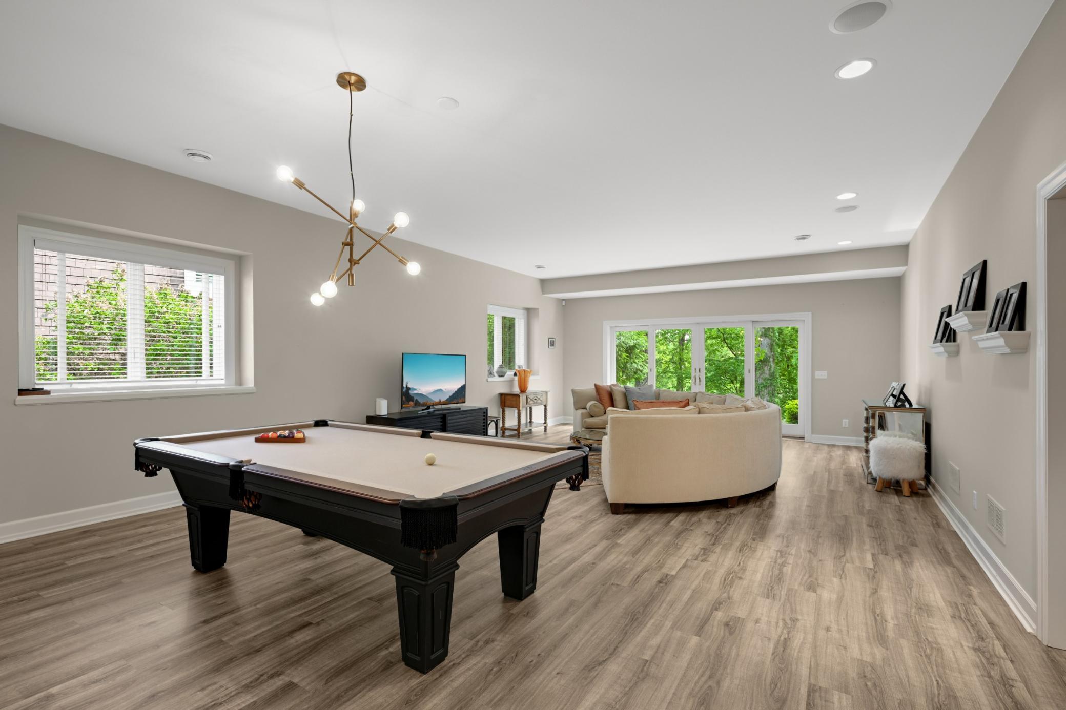 The spacious walkout level’s family room and billiard area have 9’7” ceilings, new LVT flooring and a sliding door to the patio and lake.