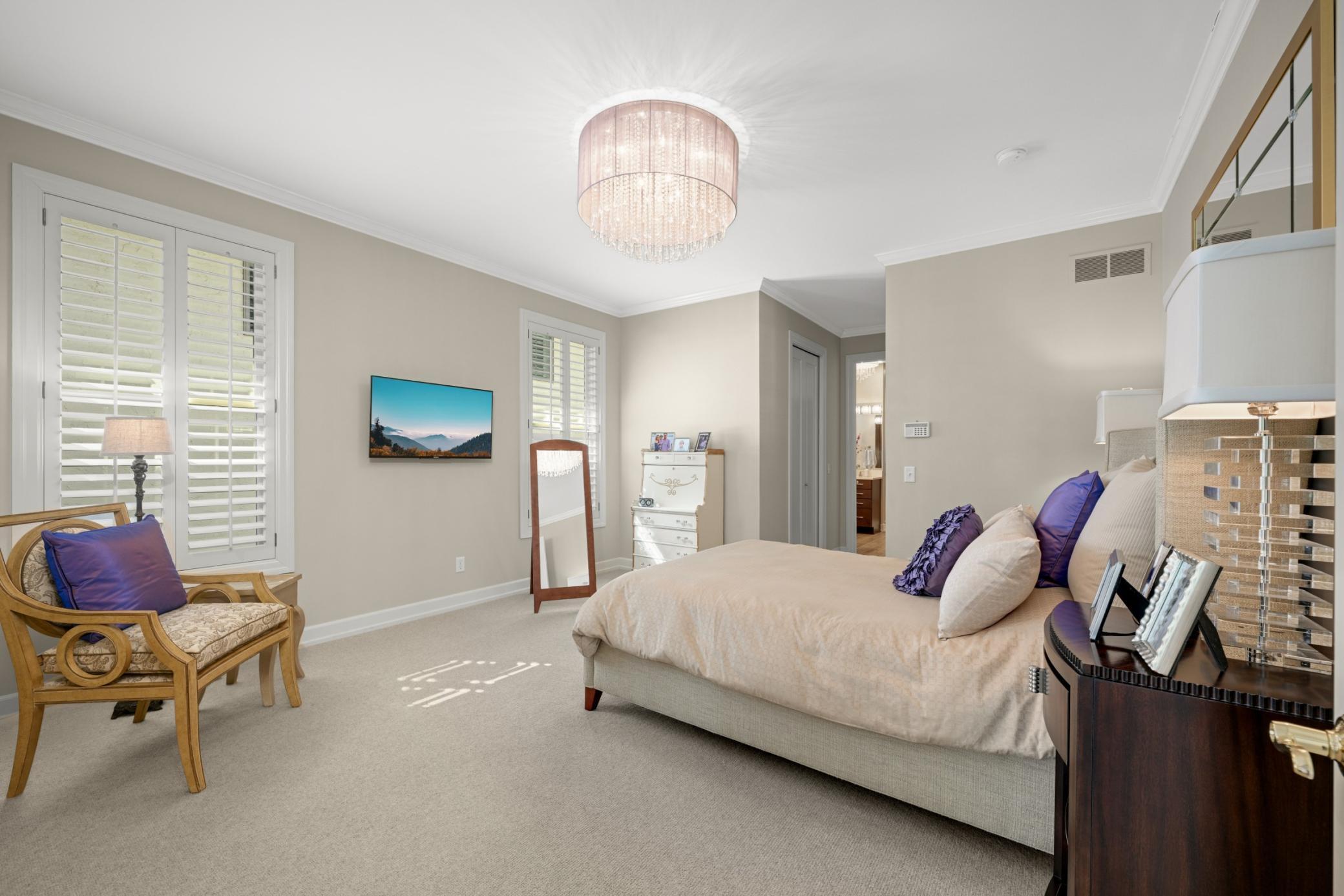 The spacious main floor primary suite has two southern exposure windows with plantation shutters and two walk-in closets