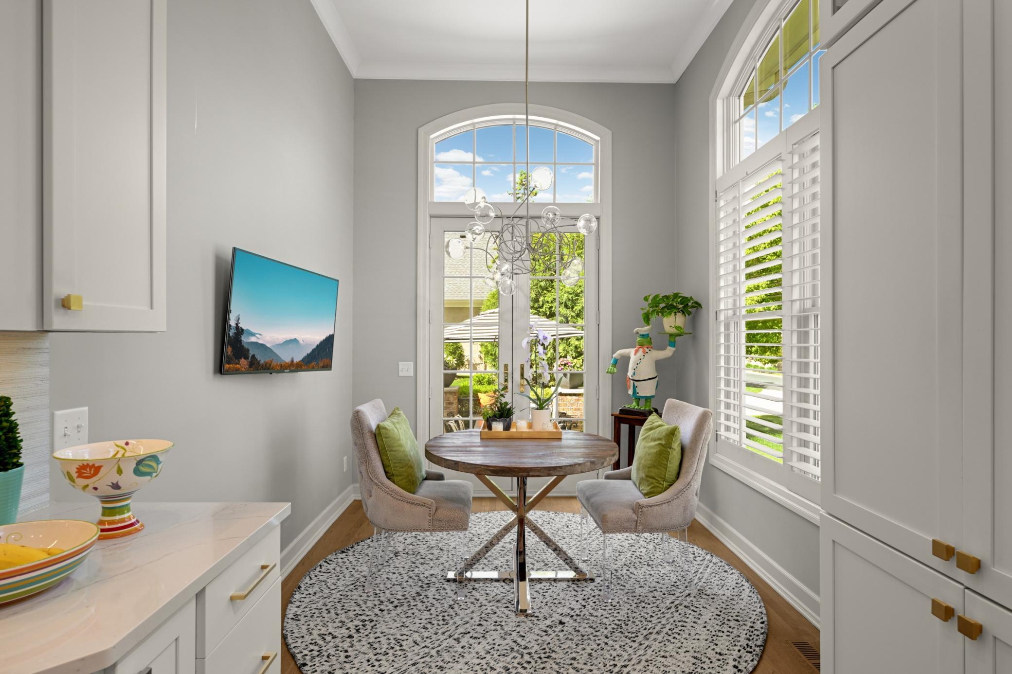 The informal dining area with a whimsical chandelier and French doors with an arched transom window to the patio.