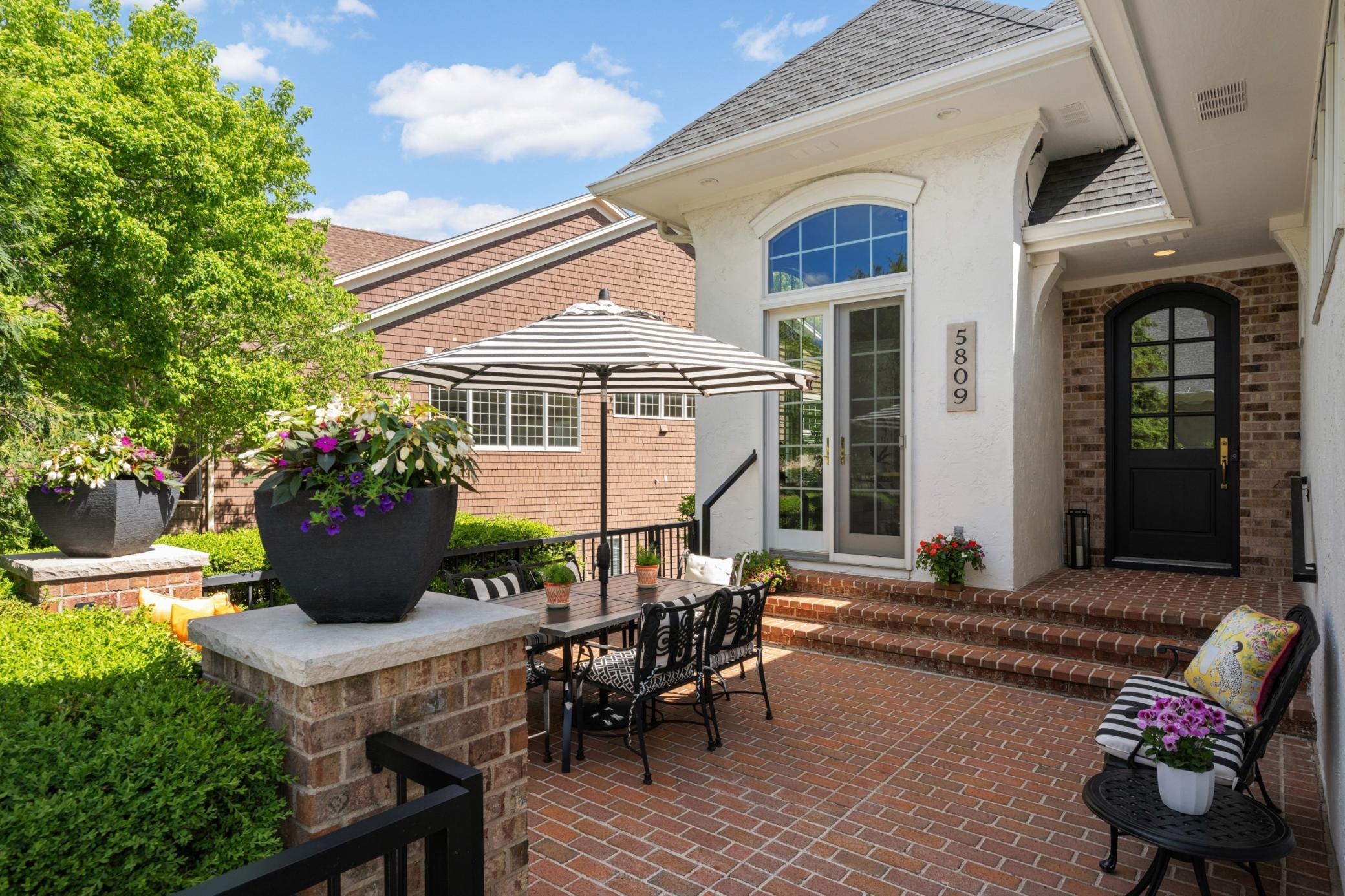 A charming red brick courtyard patio welcomes you to the arched front door and French doors from the kitchen