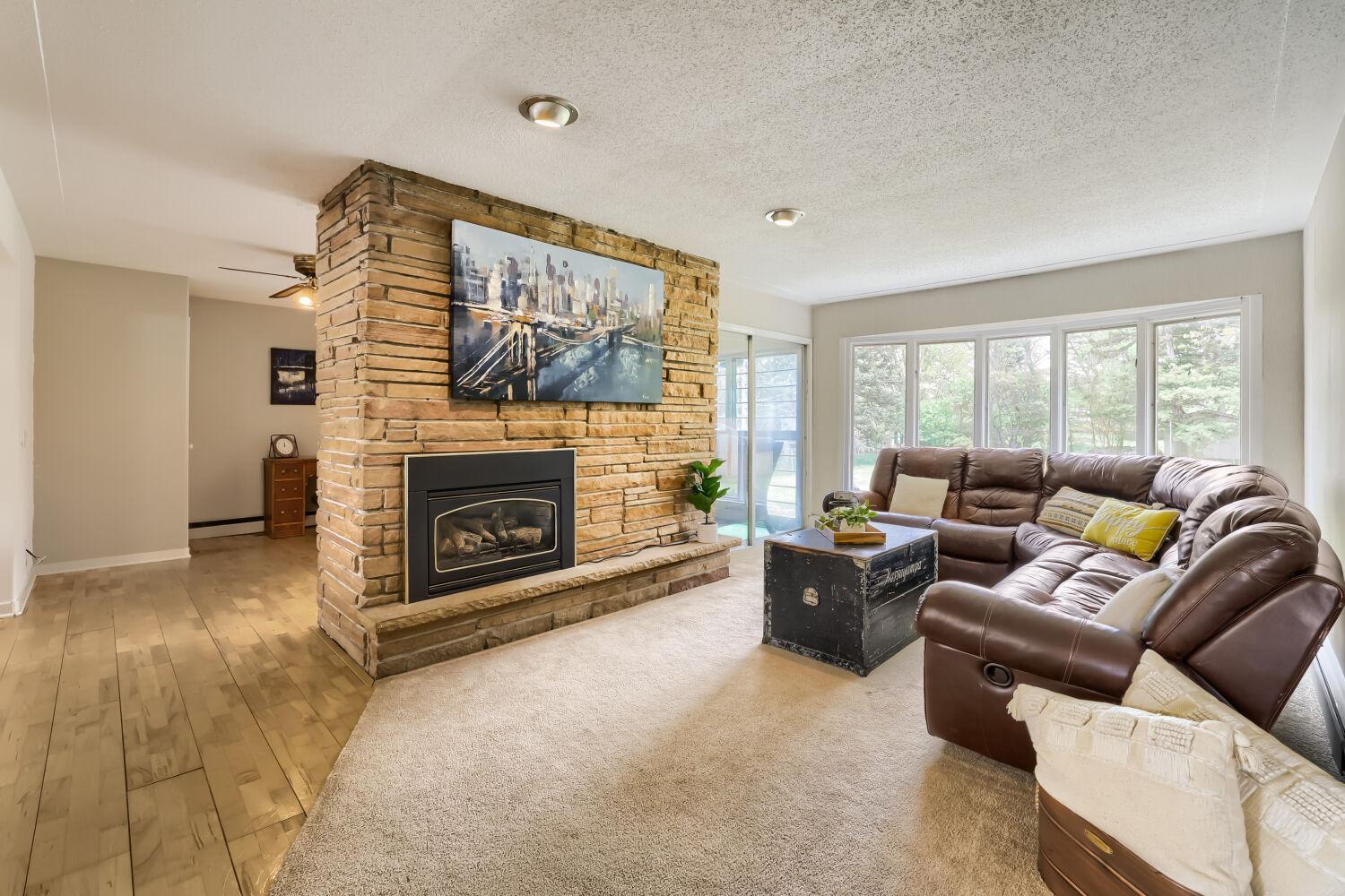 Beautiful stone gas fireplace in a big and bright living room open to the kitchen and dining room