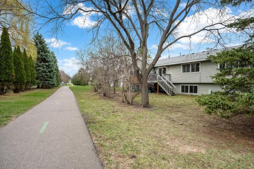 The home rear shows the walkdown deck and the adjacent trail system to the neighborhood parks.