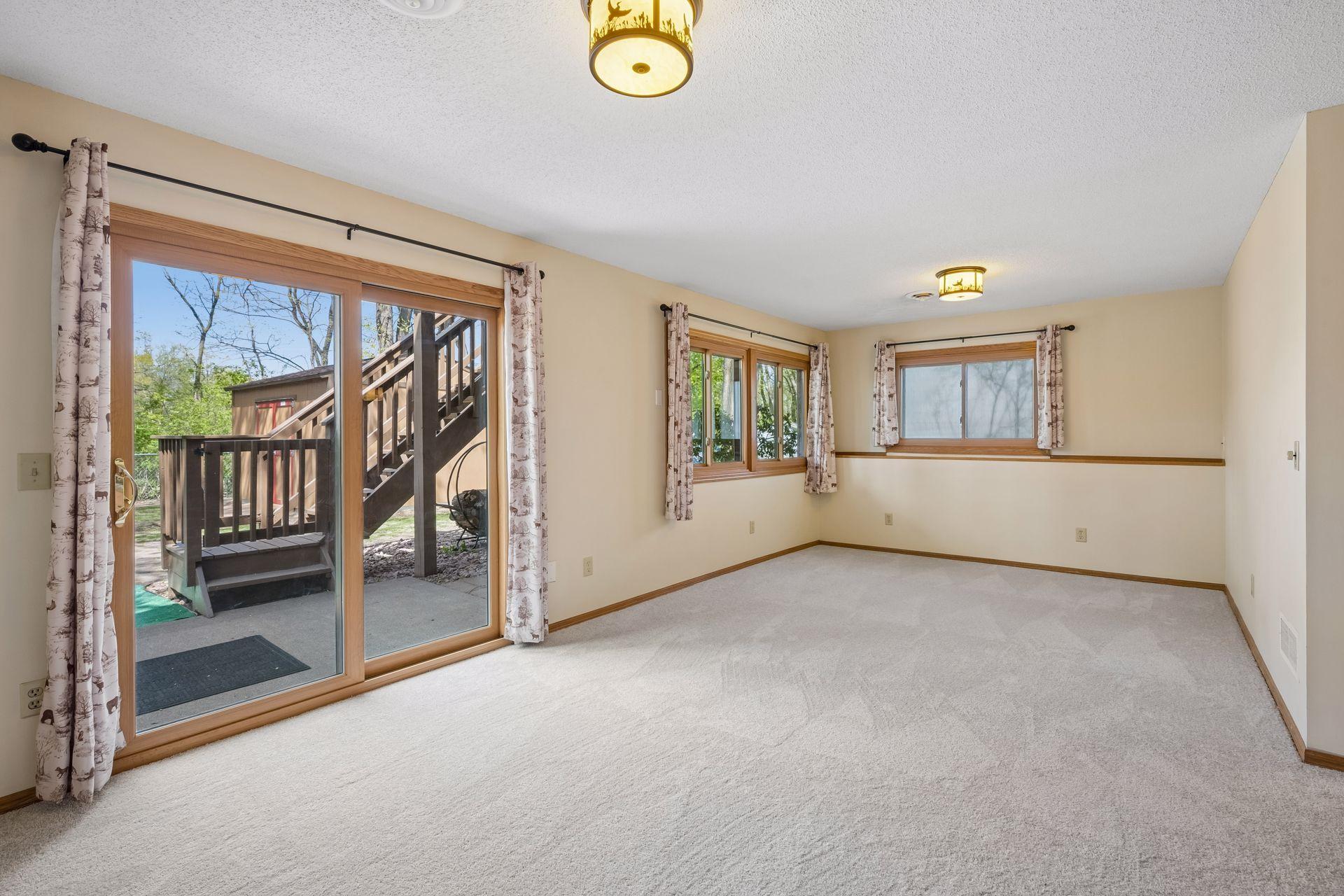 Lower level looking out the patio door to the outdoor patio space and stairs going up to the deck