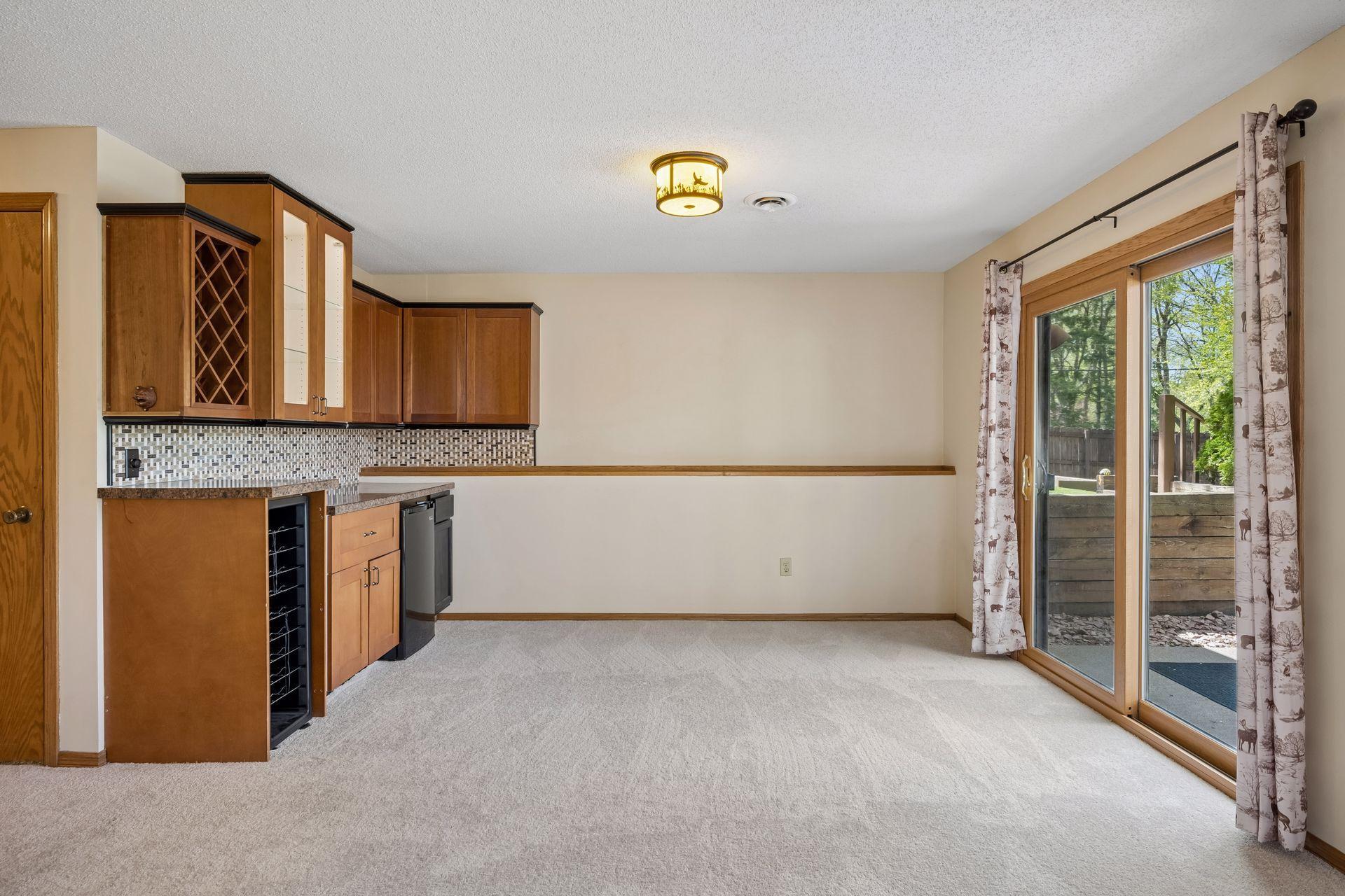 Lower level bar area has mini fridge and wine rack with easy access to the outdoor patio and backyard