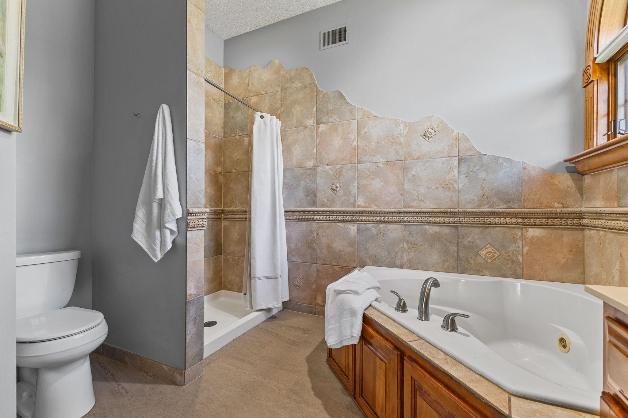 The private primary bath offers a separate custom artistically tiled shower creating that pristine spa like ambiance.