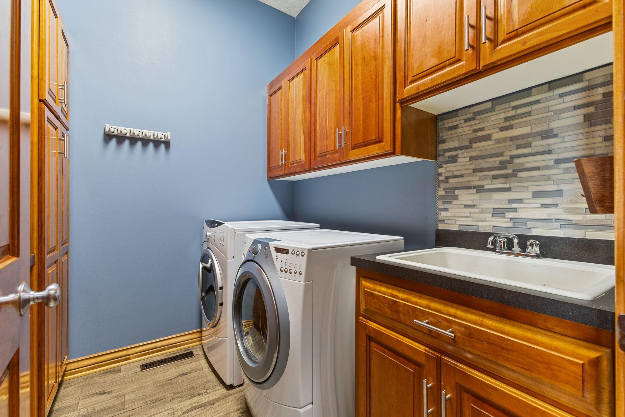 Main level spacious laundry room with ample storage and folding surfaces.