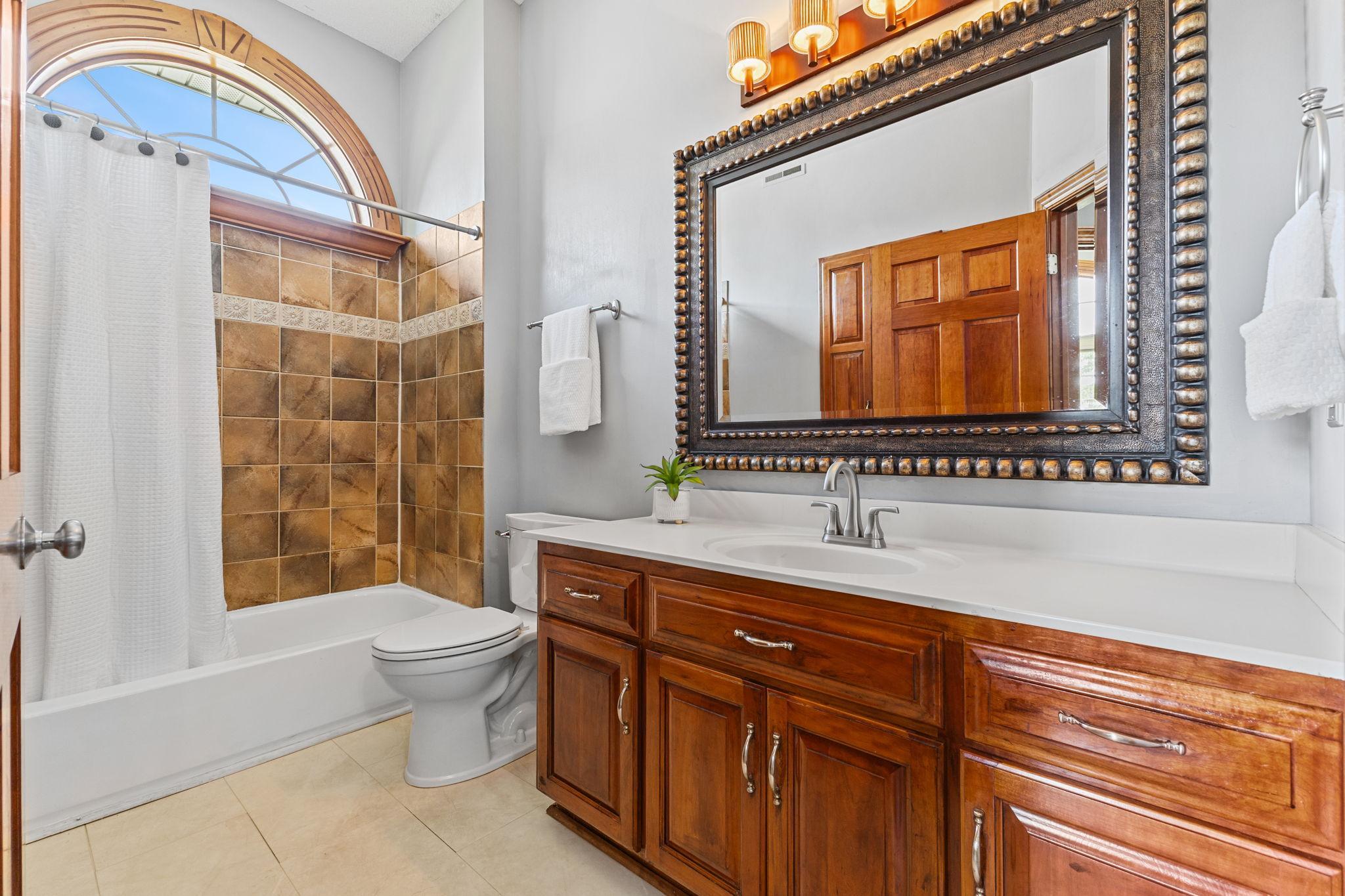 This second full bath on the main level features a tile bath/shower, designer mirror & fixture and a beautiful arched window to fill the space with natural light.