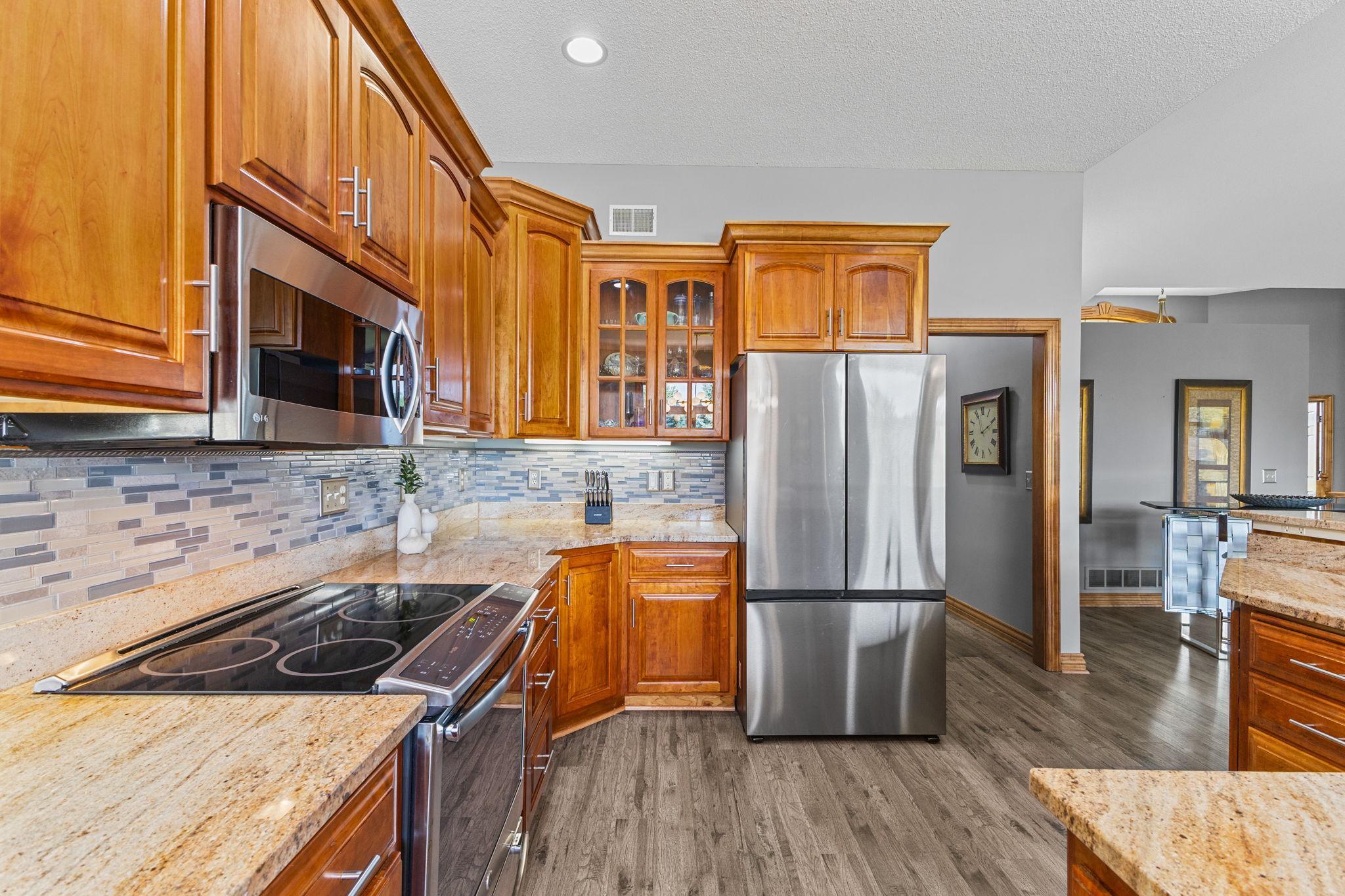 Spacious kitchen with an abundance of storage including quality custom cabinetry details with additional display storage, paneled doors & crown molding. The designer backsplash is showcased by undercabinet lighting in this sleek & modern kitchen.