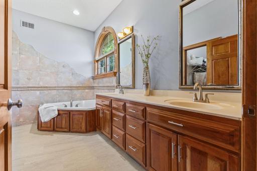 Private primary bath features a jetted soaking tub, new LVP floors (2026), and dual vanities plus walk in closet access allowing for a comfortable reset each morning.