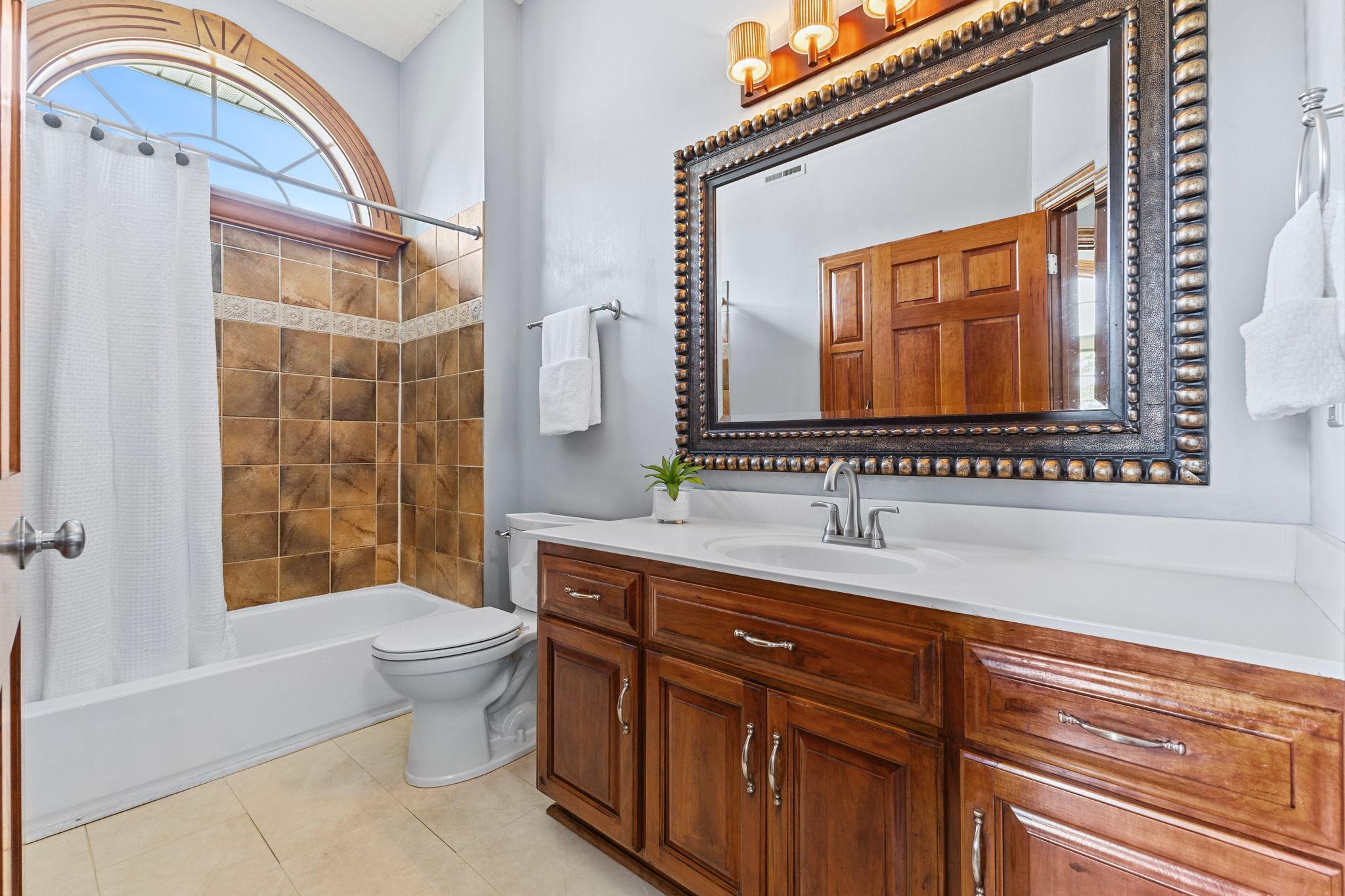 This second full bath on the main level features a tile bath/shower, designer mirror & fixture and a beautiful arched window to fill the space with natural light.