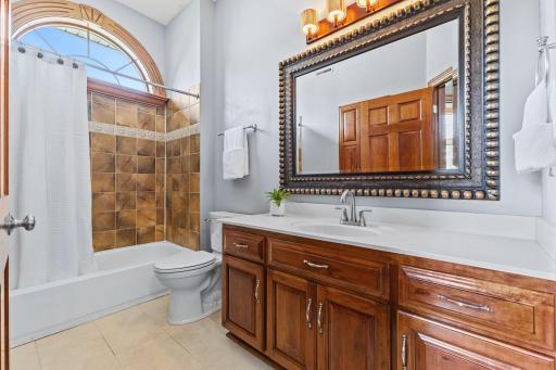 This second full bath on the main level features a tile bath/shower, designer mirror & fixture and a beautiful arched window to fill the space with natural light.
