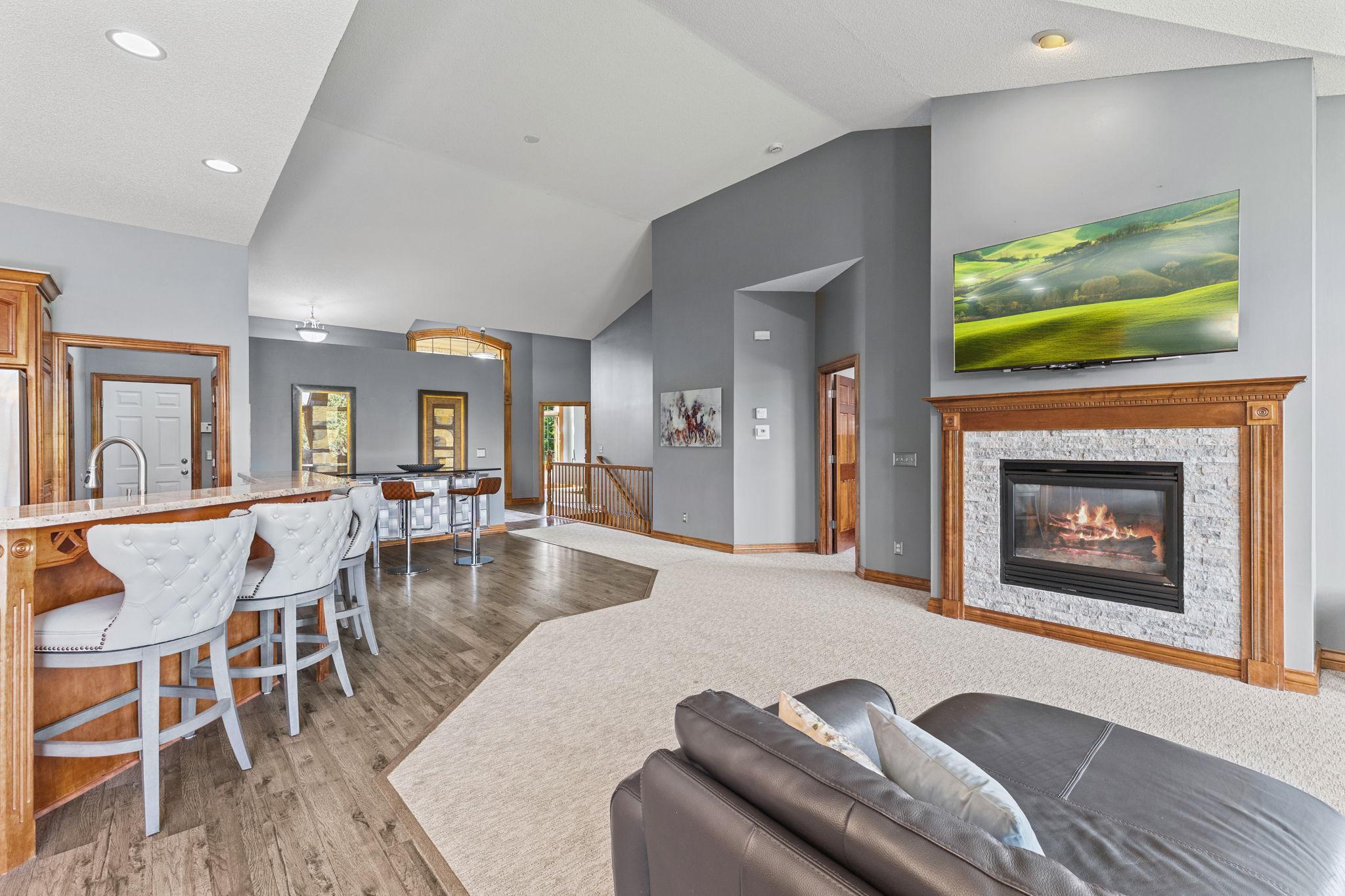 The cozy gas fireplace offers a stunning modern focal point with the newer custom natural brick surround. Vaulted ceilings create a grand feel to the main level living room.