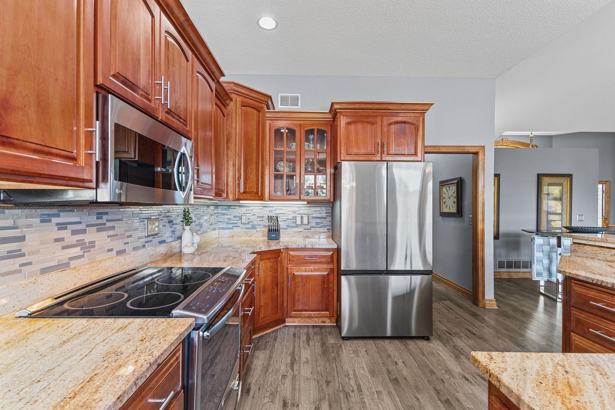 Spacious kitchen with an abundance of storage including quality custom cabinetry details with additional display storage, paneled doors & crown molding. The designer backsplash is showcased by undercabinet lighting in this modern & updated kitchen.