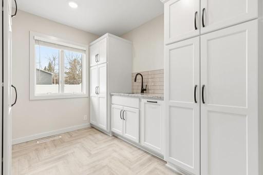 Dedicated main floor laundry room with a sink, slow close cabinetry, and ample storage!