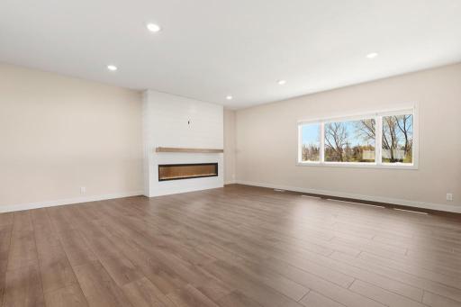 The living space features luxury vinyl plank, an electric fireplace, beautiful natural light, and a great flow to the back yard patio!