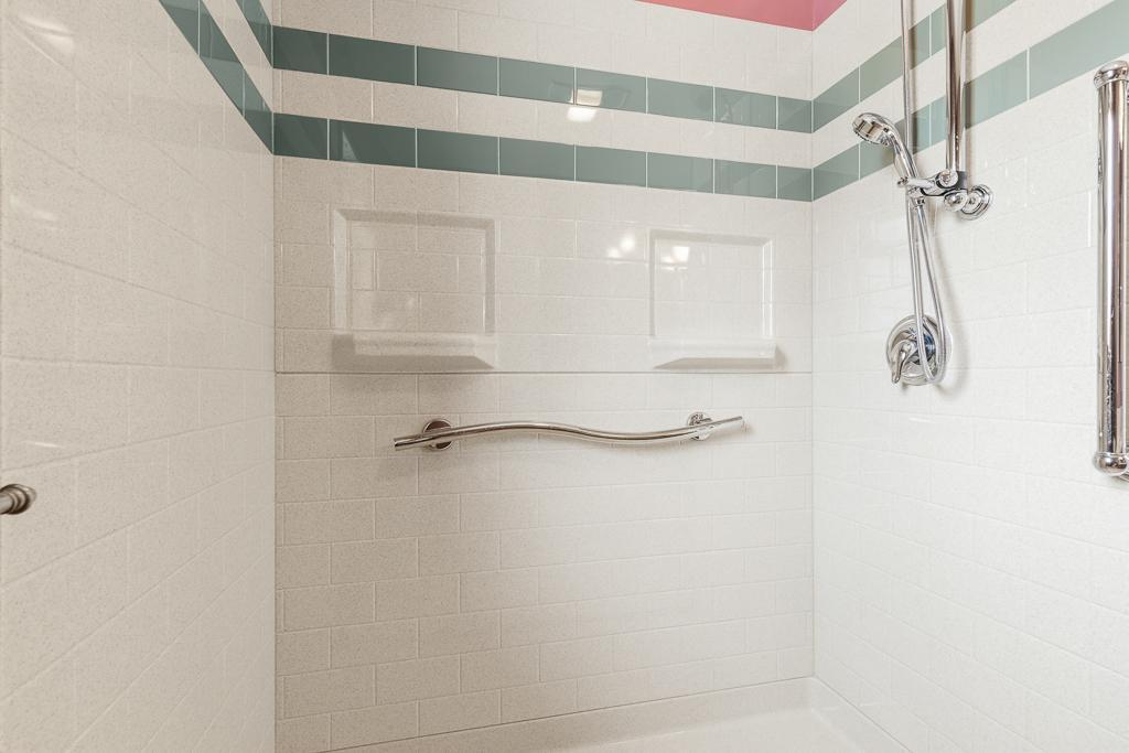 Walk-in shower with grab bars and onyx surround.