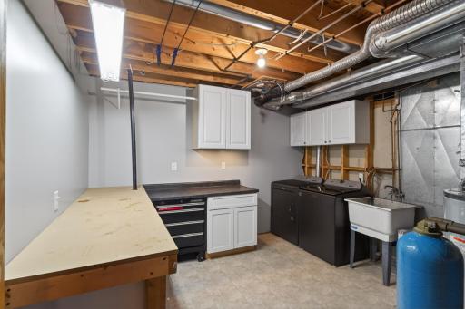 Large utility room with new high efficiency furnace and AC, newer high end large capacity washer and dryer, water softener, cabinets, and laundry sink!