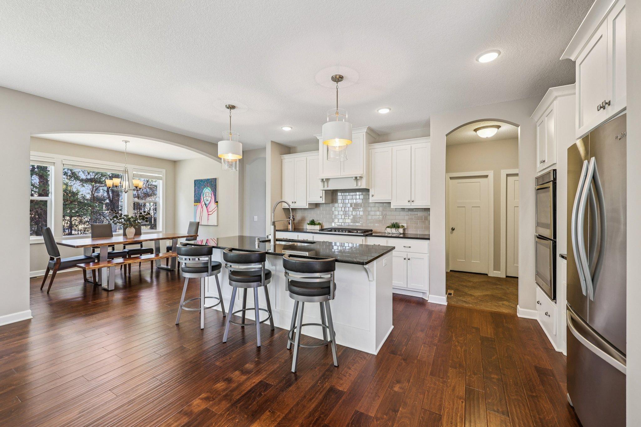 Spacious kitchen with site finished cabinetry, subway tile backsplash, double wall oven, and oversized center island with seating.