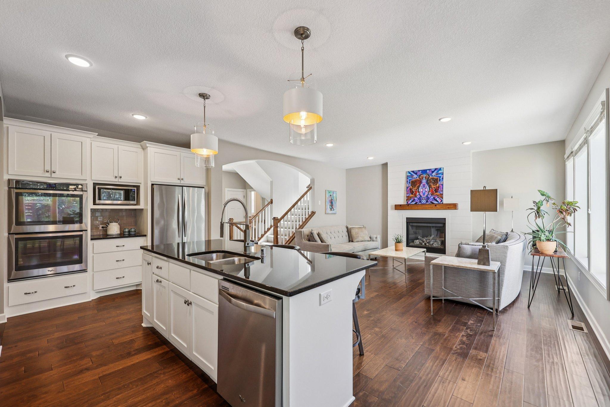 Open concept kitchen and living area with large center island, granite countertops, stainless appliances, and abundant natural light.
