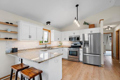 The updated white kitchen is a chef's delight, complete with granite countertops, a convenient breakfast bar, stainless steel appliances, and a stylish tile backsplash