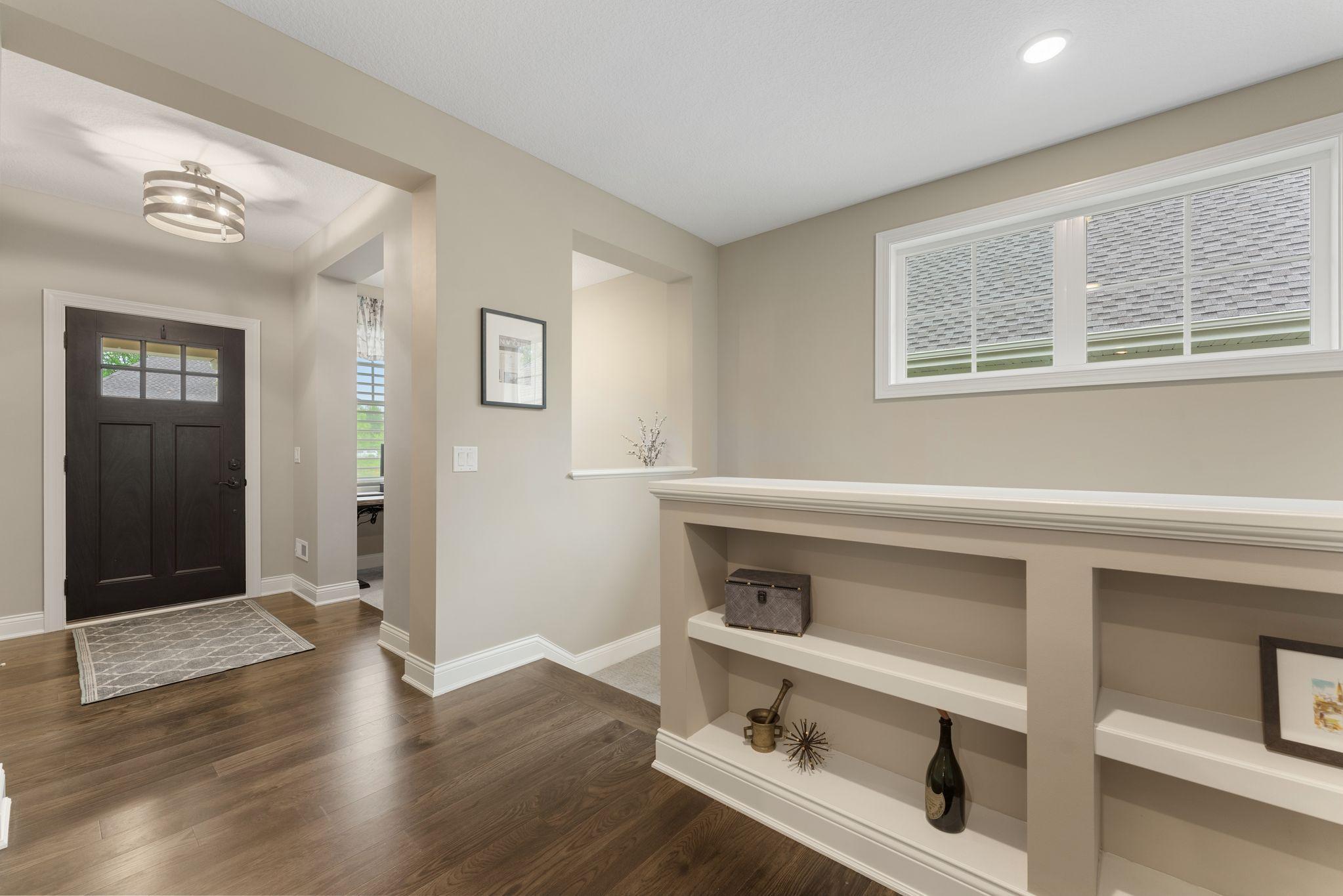 The Foyer has wonderful space and light coming in -- the hall, leads to the living space/kitchen -- gorgeous built-in shelving and transom windows. The use of space and light within the home is so beautiful!