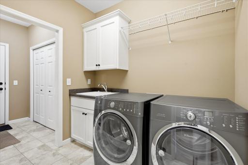You can access the main floor laundry from the primary closet, and also from the back entry from garage. This shows the tile area including sink in laundry and closet coming in from the garage