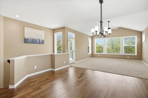 Formal dining area with hardwood floors, showing great room in back, stairs to lower level, and door out to main level deck
