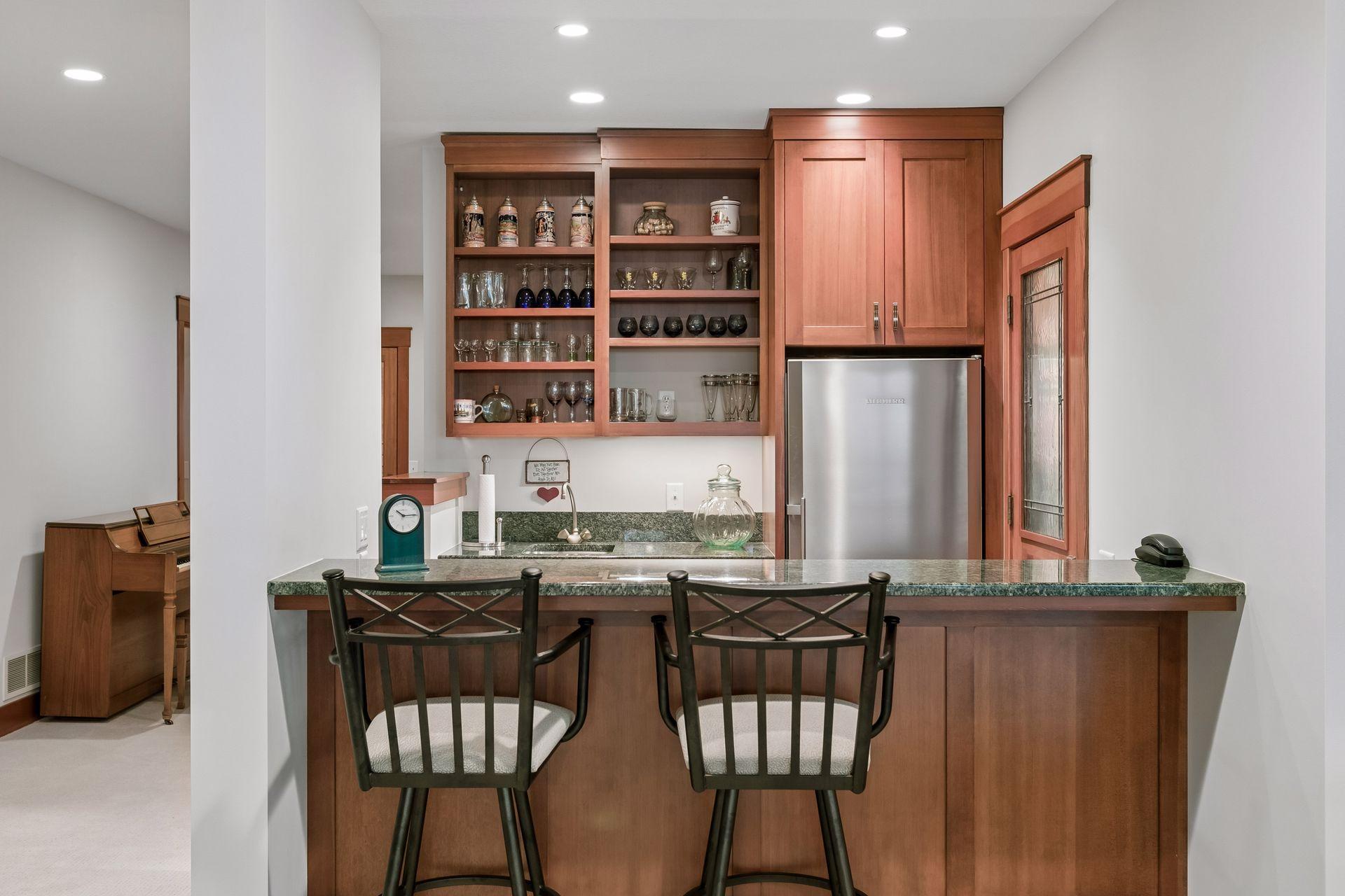 Wet bar featuring granite countertops, refrigerator/freezer, and bar seating, perfect for entertaining.