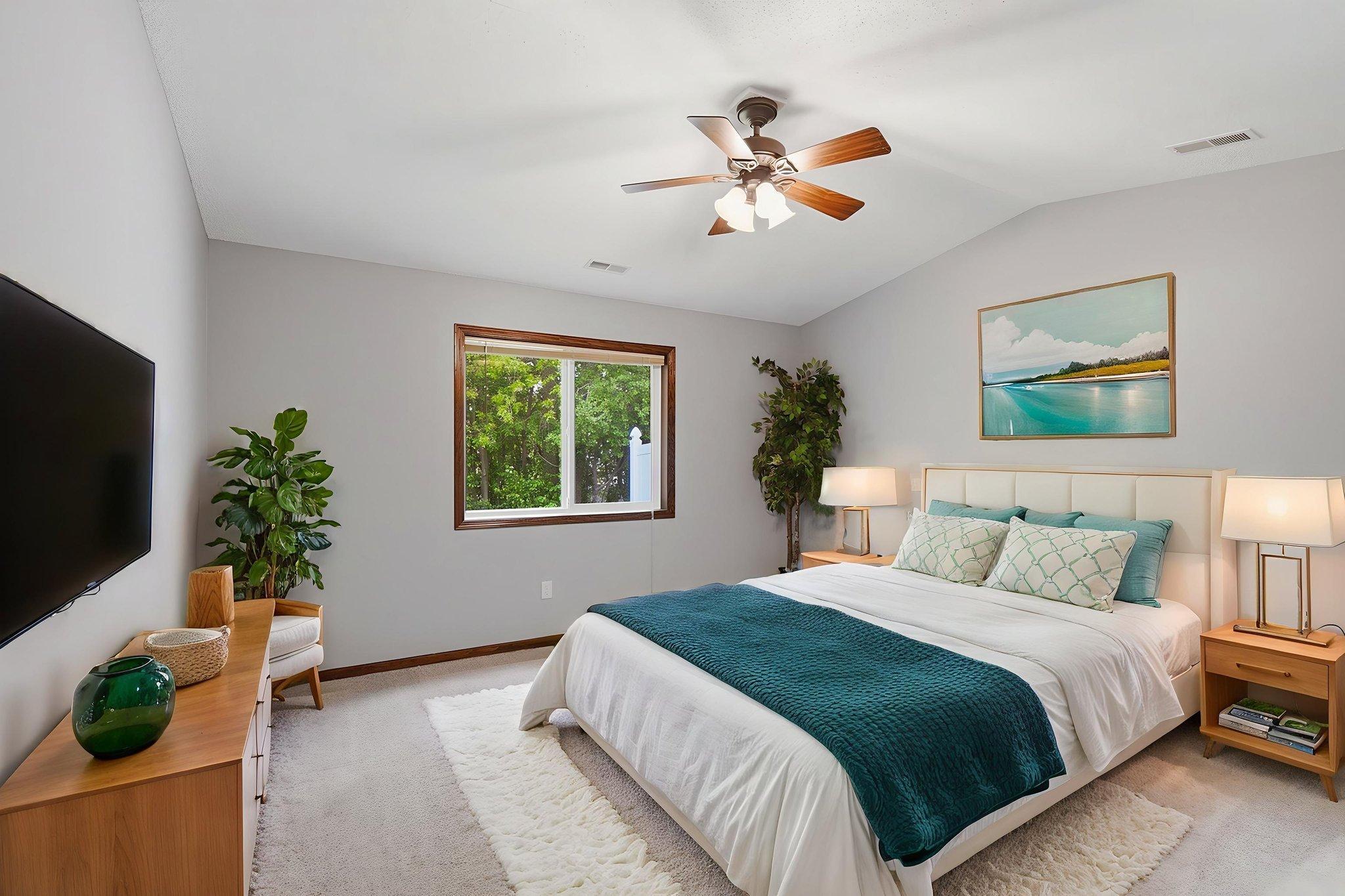 Bright and inviting bedroom with soft neutral tones, and a large window overlooking lush greenery.