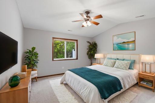Bright and inviting bedroom with soft neutral tones, and a large window overlooking lush greenery.
