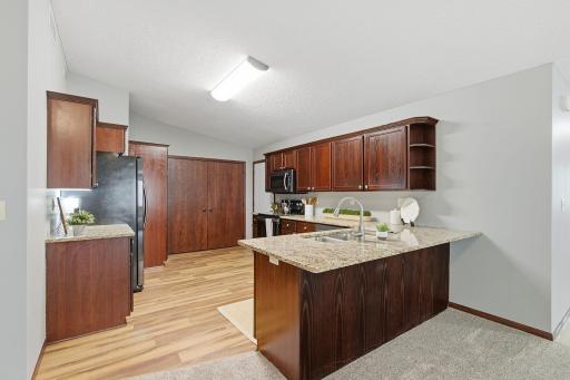 Modern kitchen with rich wood cabinetry, granite countertops, stainless steel appliances, and a convenient peninsula with sink.